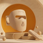 Hello Face M300 beige silicone LED mask with handheld controller in a warm studio setting